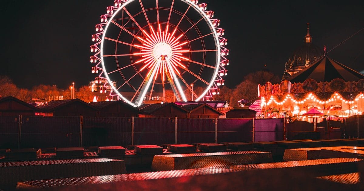 Beleuchtetes Riesenrad und Karussell auf einem Volksfest bei Nacht